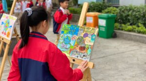 A student wearing a jacket works on art showcasing plastic's environmental impacts