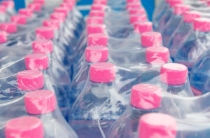 Pink screw cap of water bottles in plastic wrap, a single use plastic