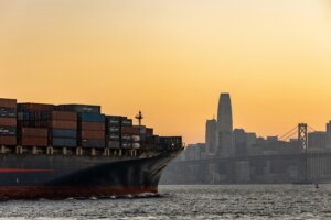 Cargo ship sails into the Port of Oakland at sunset.