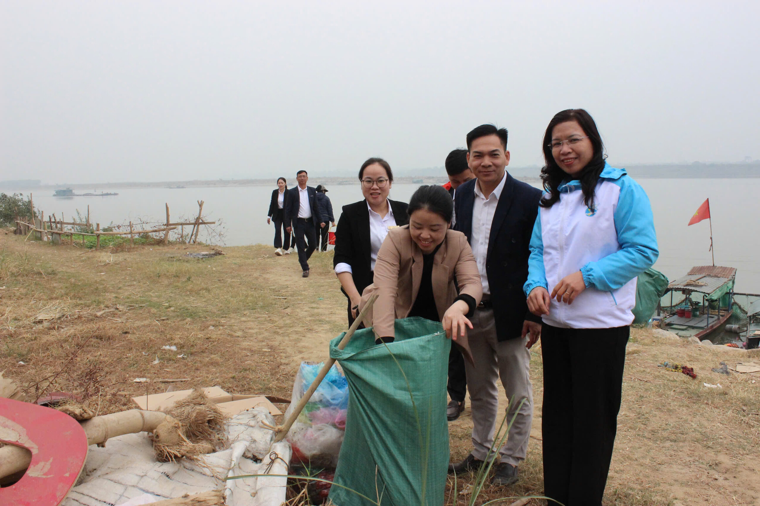 Group of volunteers putting trash in garbage in trash bag
